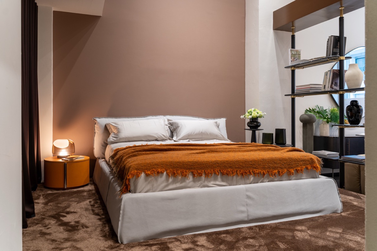 Camera da letto Baxter con letto in pelle e coperta arancione nello showroom