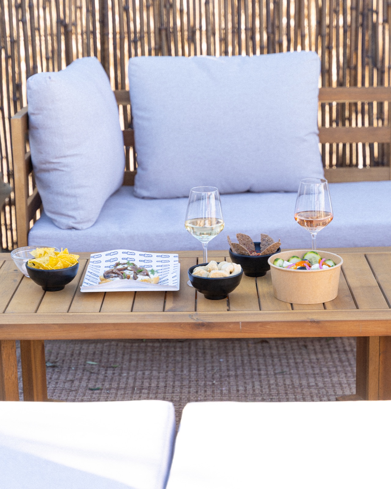 Divanetto all'aperto con calici di vino e piattini da aperitivo, Casa Santo