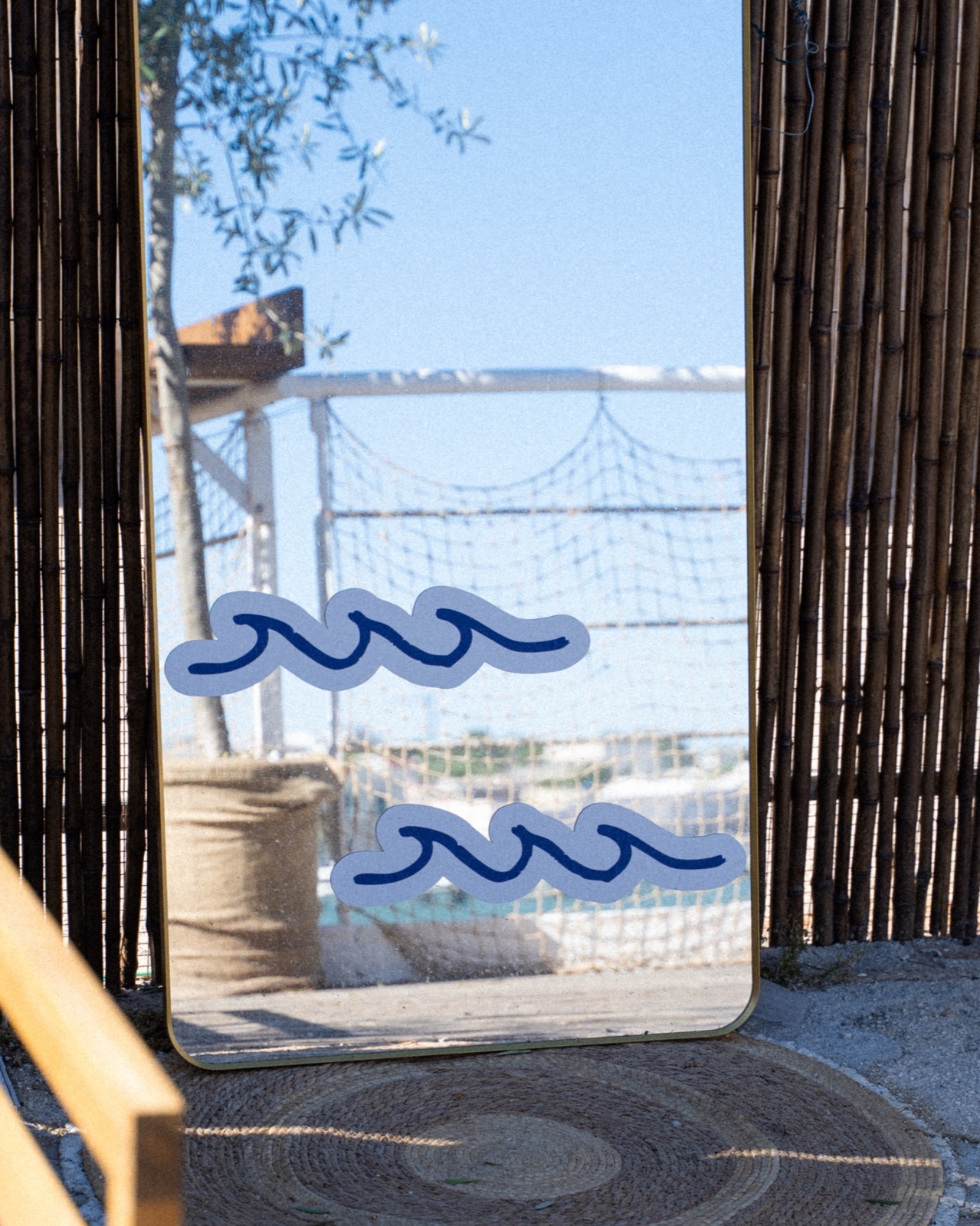 Specchio con onde blu dipinte tra pareti di bambù, dettaglio di Casa Santo