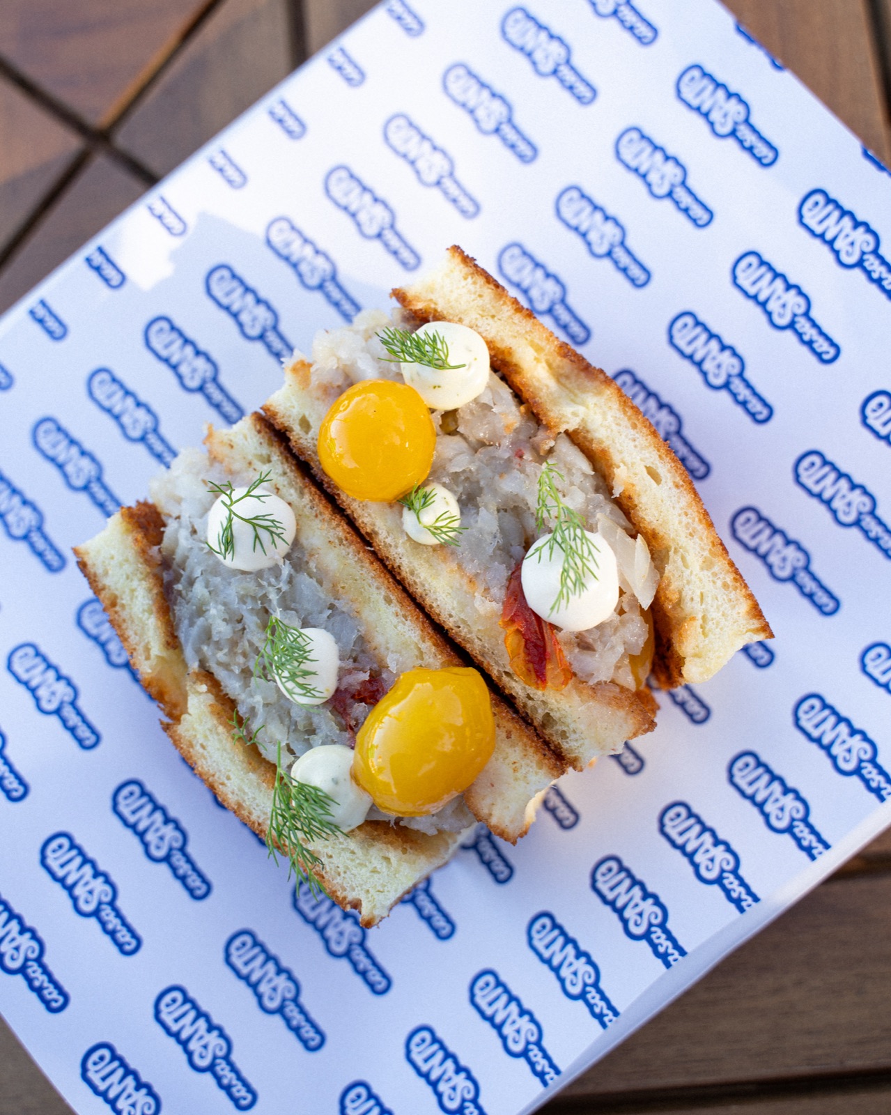 Mediterraneo Sando: tramezzino tostato con tuorli e verdure su carta con logo Casa Santo
