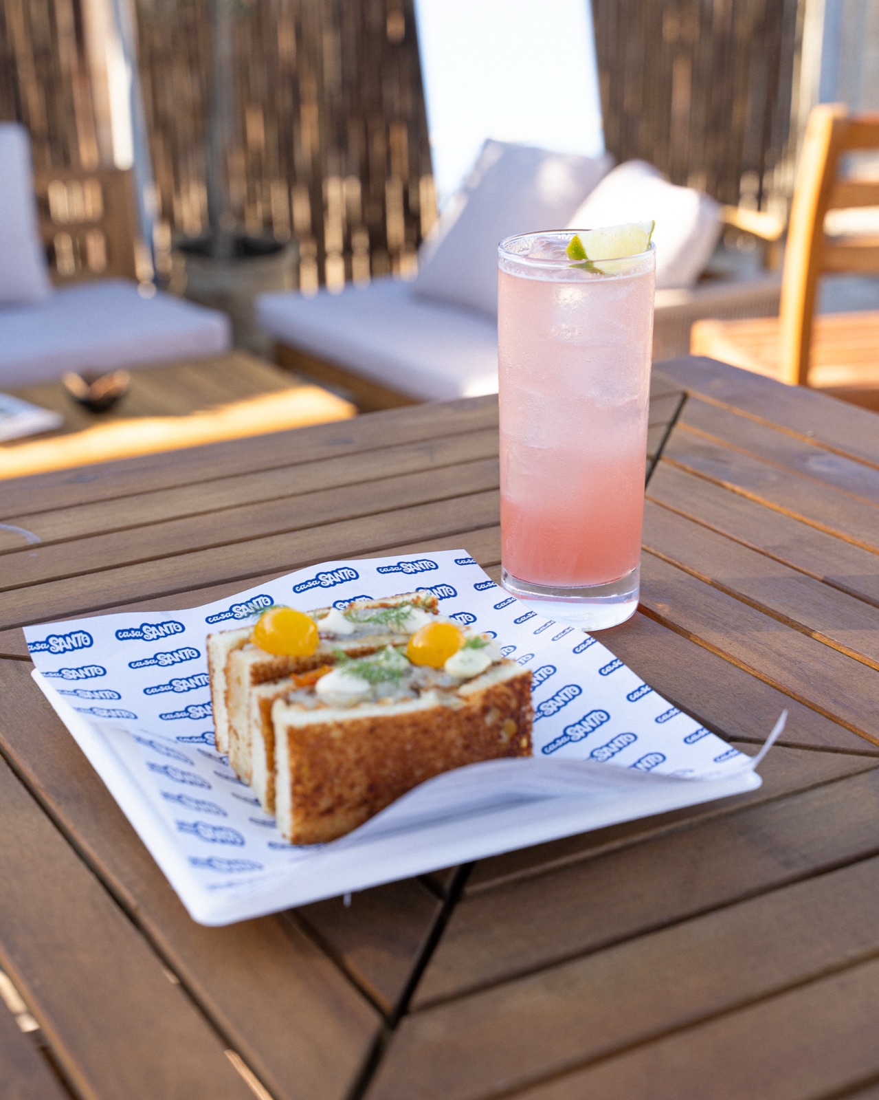 Cocktail rosa con lime e sando su tavolo all'aperto, Casa Santo
