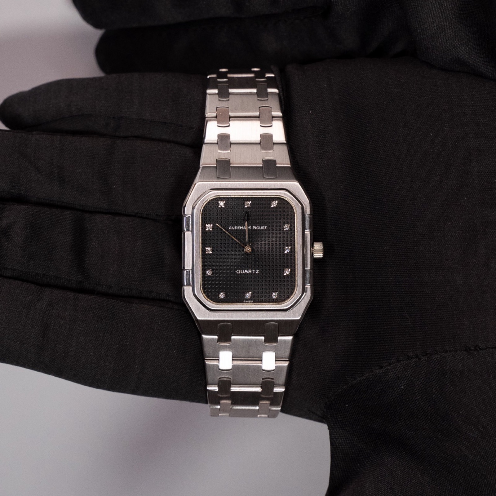 Orologio Audemars Piguet in acciaio tenuto da una mano in guanto nero, Chiossone Luxury Watches