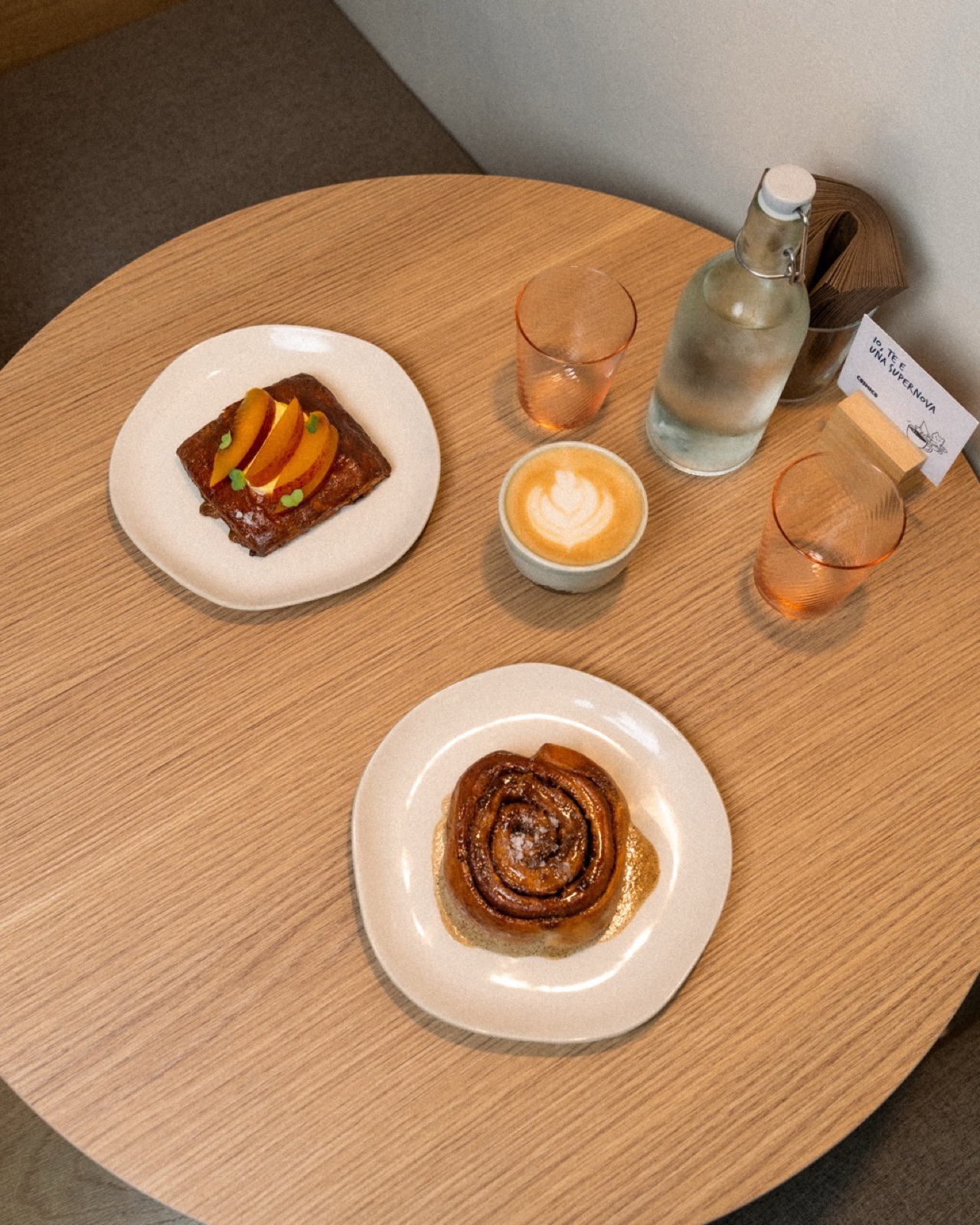Tavolo con cappuccino, cinnamon roll e dolce alla frutta visto dall'alto, Cosmico