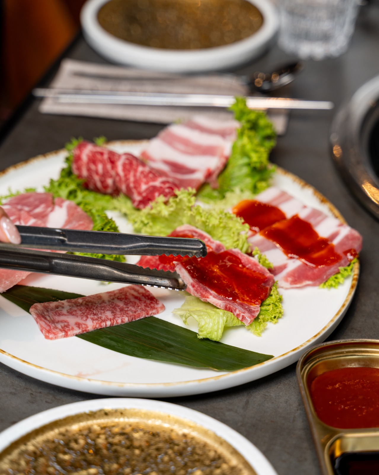 Tagli di carne per barbecue coreano con salse sul tavolo, Sentò