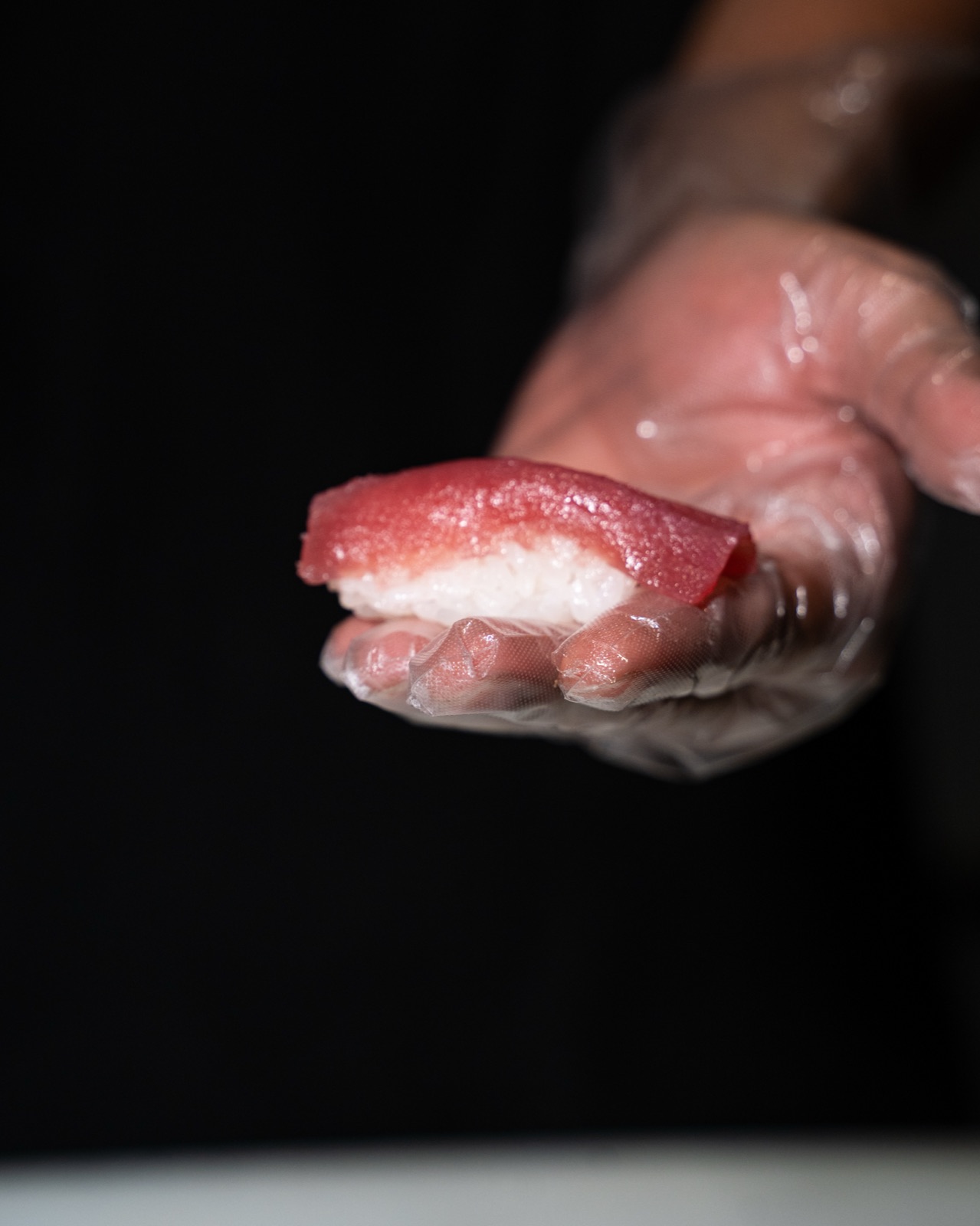 Nigiri di tonno nel palmo della mano dello chef, Yuzu
