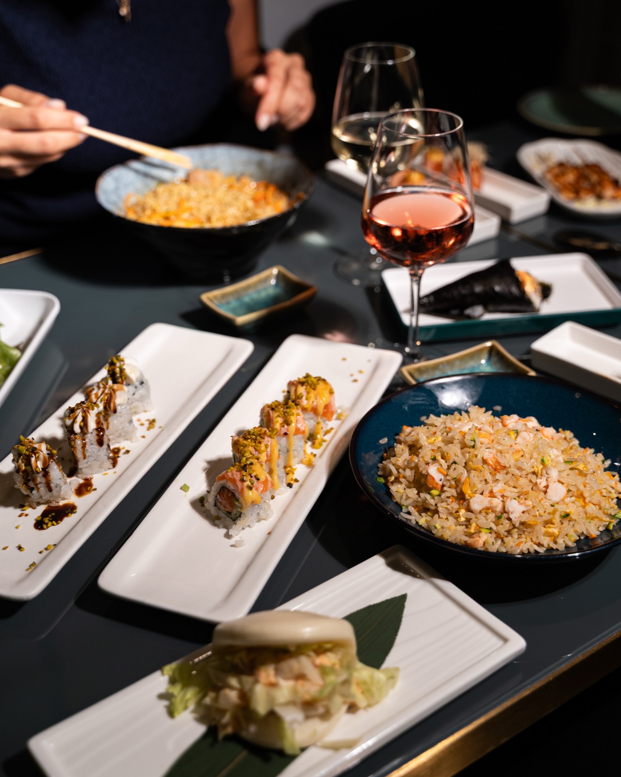 Tavola imbandita con sushi, riso saltato e calici di vino, Yuzu Bari